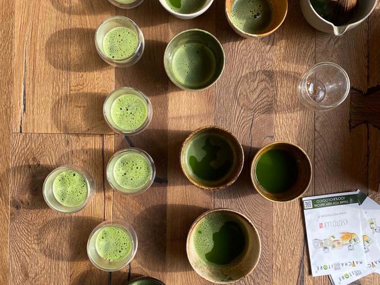 Hotel Latemar mit Dolomitenblick Tassen und Gläser mit grünem Matcha-Tee auf Holztisch