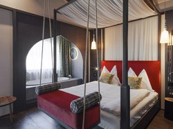 Hotel Latemar mit Dolomitenblick Modernes Schlafzimmer mit rotem Himmelbett und Whirlpool-Badewanne