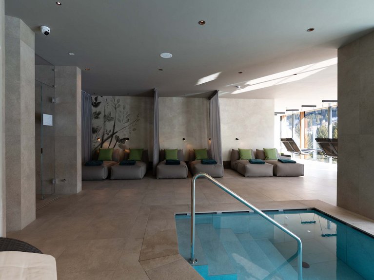 Hotel Latemar mit Dolomitenblick Ruhebereich mit Liegen und Innenpool in einem modernen Spa