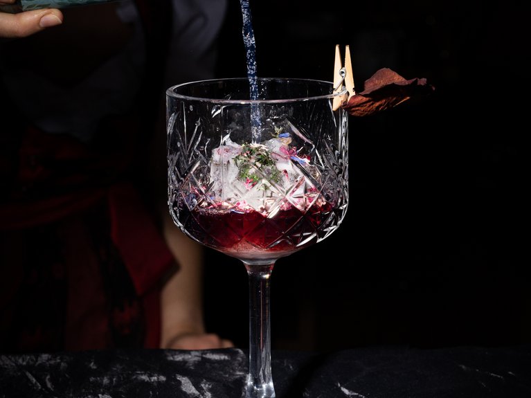 Hotel Latemar mit Dolomitenblick Flasche Tirol Tonic gießt in ein Glas mit Cocktail und Eiswürfeln