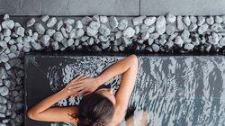 Hotel Latemar mit Dolomitenblick Frau entspannt im Pool mit Kieselsteinen rundum, Draufsicht