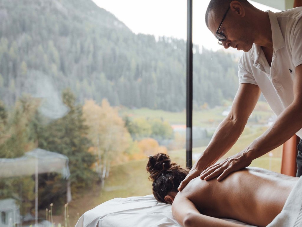 Hotel Latemar mit Dolomitenblick Masseur massiert den Rücken einer Frau in einem Zimmer mit Bergblick