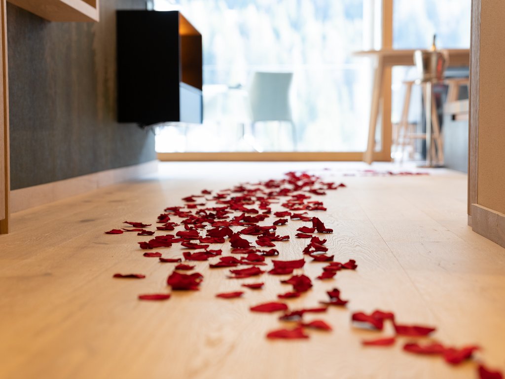 Hotel Latemar mit Dolomitenblick Rote Rosenblätter auf einem hellen Holzboden in einem hellen Raum