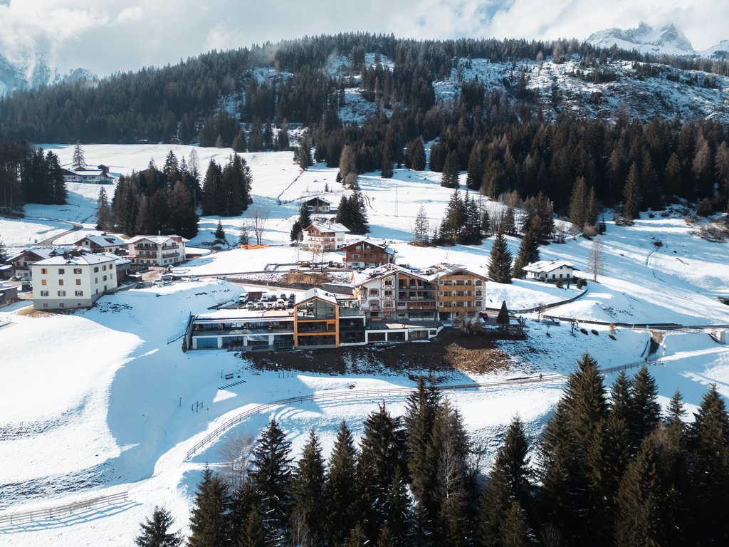 Hotel Latemar mit Dolomitenblick Verschneites Dorf am Waldrand und vor Bergen