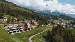 Hotel Latemar mit Dolomitenblick Hotel am Hügel mit gewundener Straße und Bergen im Hintergrund