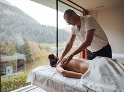 Hotel Latemar mit Dolomitenblick Masseur massiert den Rücken einer Frau im Spa mit Bergblick.