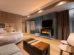 Hotel Latemar mit Dolomitenblick Modernes Hotelzimmer mit rundem Bett, elektrischem Kamin und Holzmöbeln