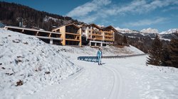 Hotel Latemar mit Dolomitenblick Langläufer auf Loipe vor Hotel in schneebedeckten Bergen