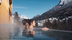 Hotel Latemar mit Dolomitenblick Menschen entspannen im Pool mit Blick auf verschneite Berge