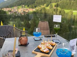 Hotel Latemar mit Dolomitenblick Tisch mit Aperitifs, Snacks und grünem Bergblick