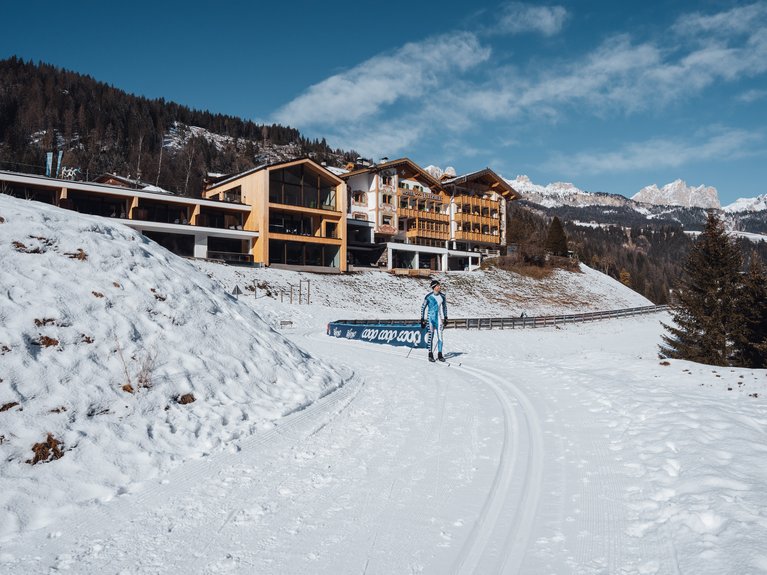 Hotel Latemar mit Dolomitenblick Langläufer auf Loipe nahe Chalet und verschneiten Bergen