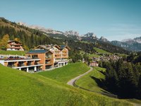 Soraga di Fassa: Wetter Modernes Hotel auf Hügel mit Blick auf schneebedeckte Berge und grünen Wald