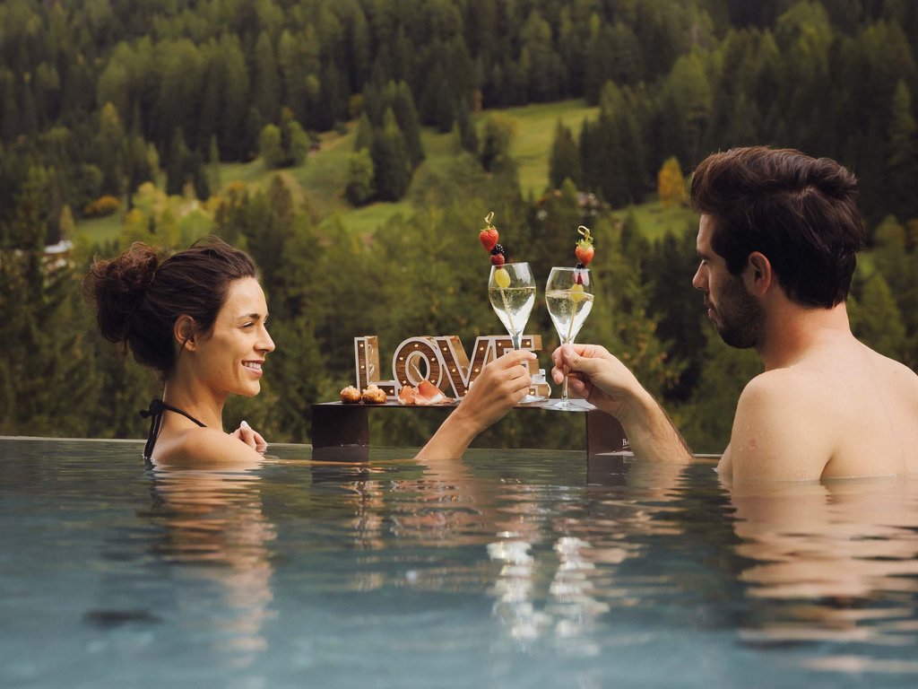 Fassatal: Radweg für romantische Momente Paar stößt im Pool mit Bergblick an