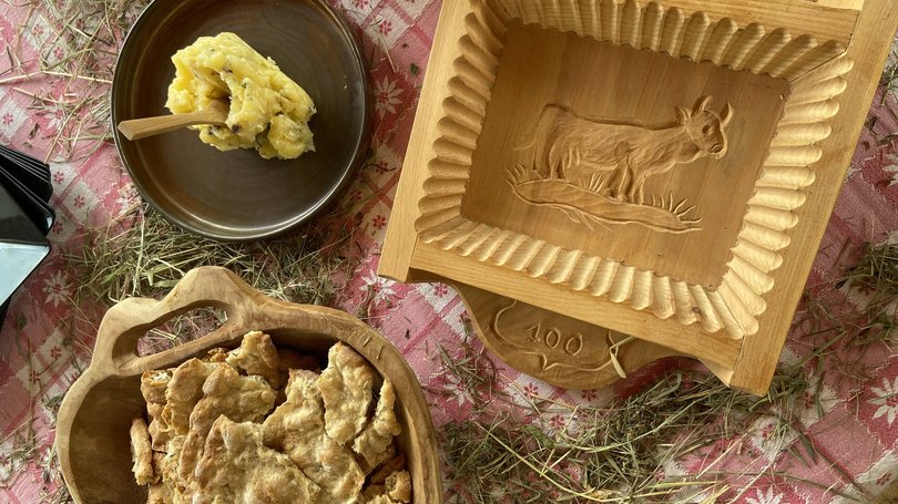 Val di Fassa: wandern, biken, erleben Knuspriges Brotgebäck und Butter auf rustikalem Tisch mit Heu und Holzform