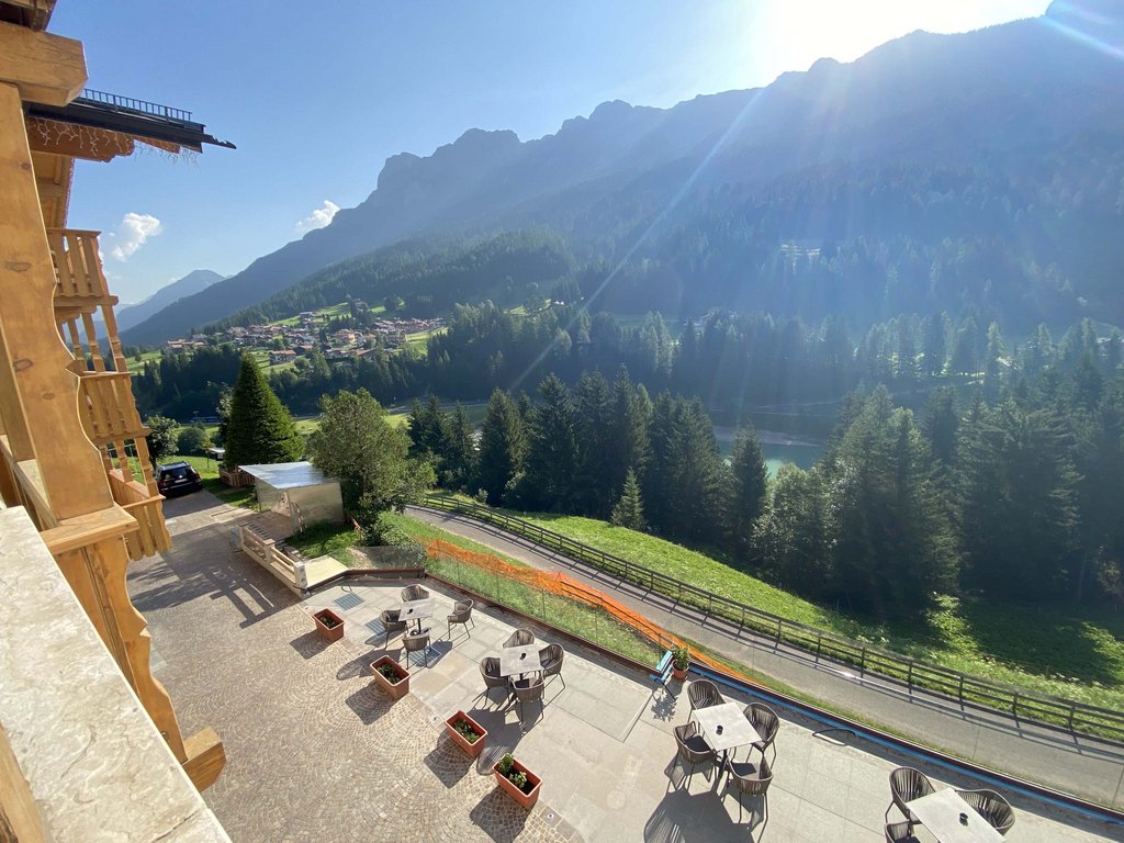 Hotel vicino a Moena: dalle 3 stelle alle 5 stelle! Terrazza con tavoli e sedie vista montagne e foresta con sole