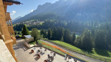 Picture gallery Terrace with tables and chairs overlooking sunny mountains and forest