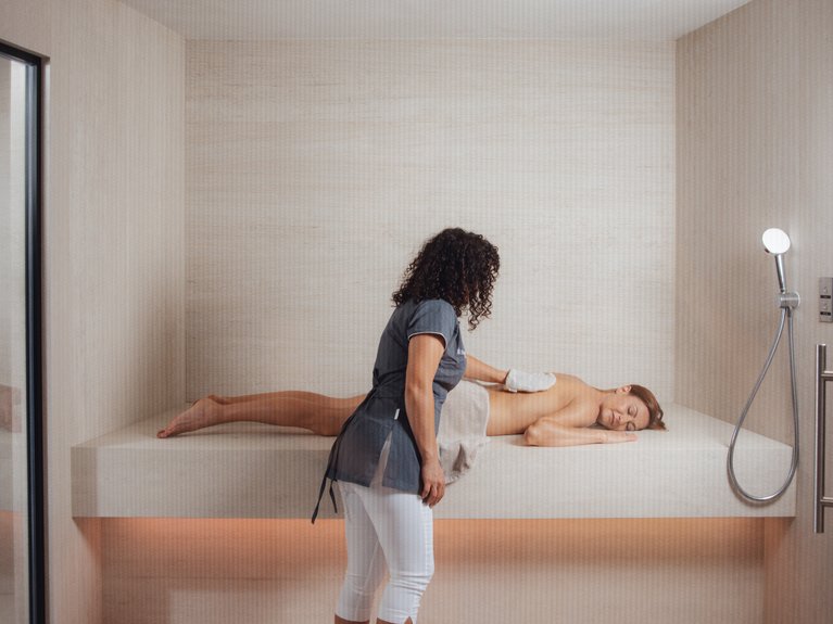 Il rituale dell’hammam al Latemar Hotel Massaggiatrice professionista che massaggia una donna distesa in una stanza luminosa