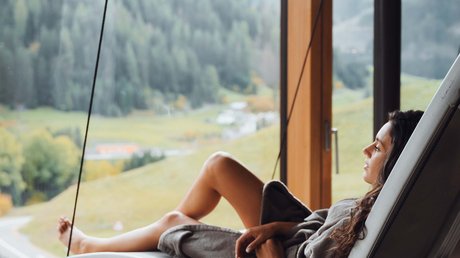 Picture gallery Woman relaxing on hanging chair by large window with mountain view