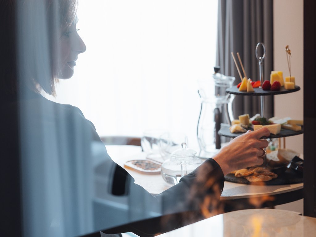 Sulla pista ciclabile, da Moena alla vostra oasi romantica Donna che prende snack da un vassoio in una stanza con camino moderno