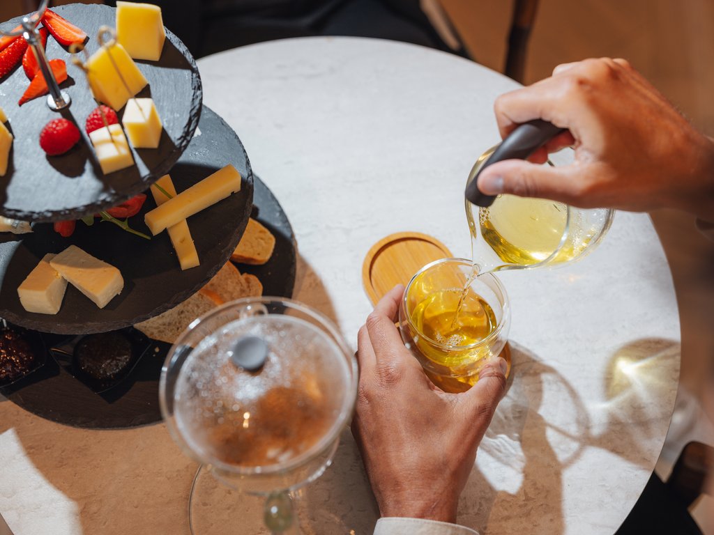 Sulla pista ciclabile, da Moena alla vostra oasi romantica Mano che versa tè e vassoio con formaggi e fragole su tavolo bianco