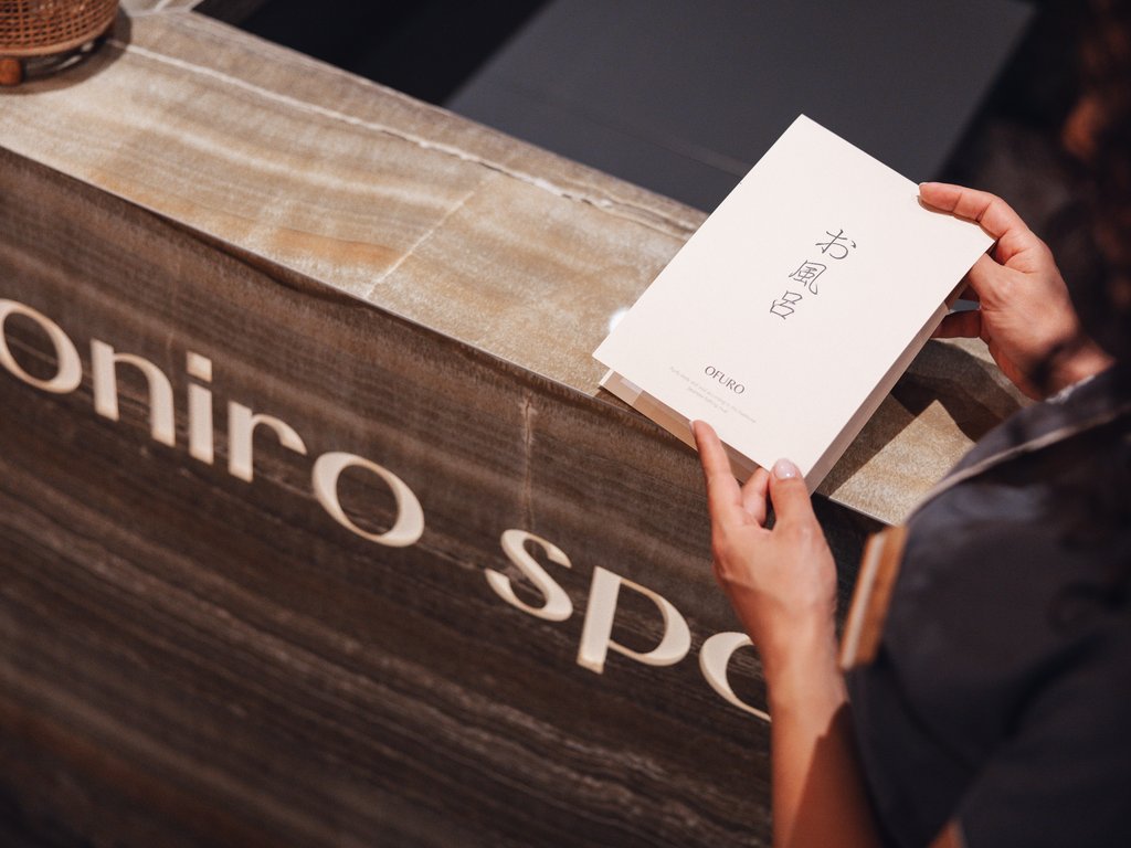 Soraga: dal lago alla piscina del Latemar Persona che tiene un menu spa presso il banco di accoglienza Onirico Spa