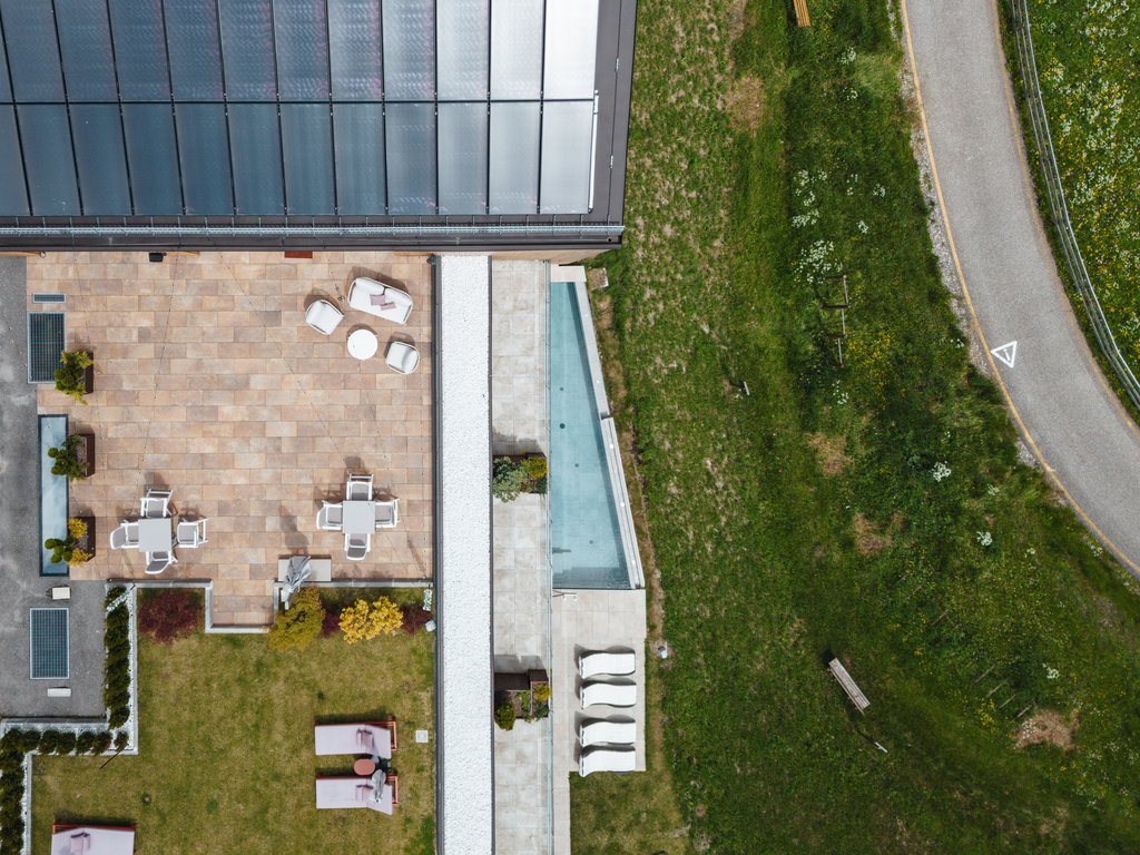 Barrierefreies Hotel im Val di Fassa: das Latemar Drohnenaufnahme einer Terrasse mit Stühlen, Tischen und angrenzendem Gras