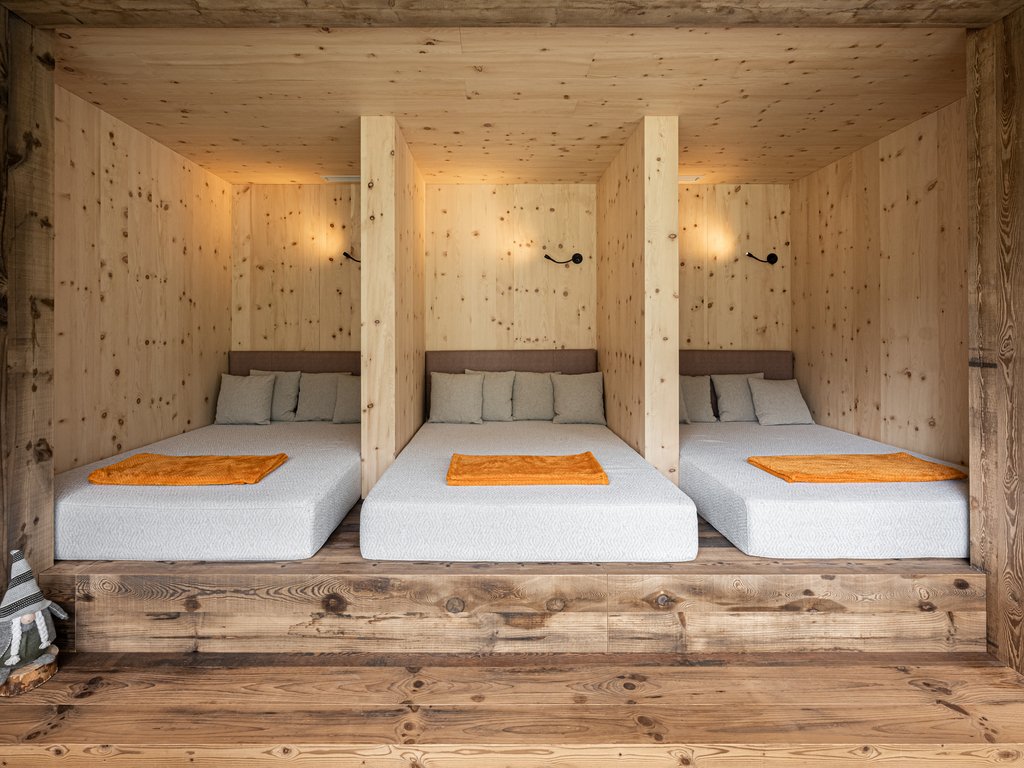 In Soraga, the weather is always right for a day spa! Three single beds separated by light wood walls in a rustic room
