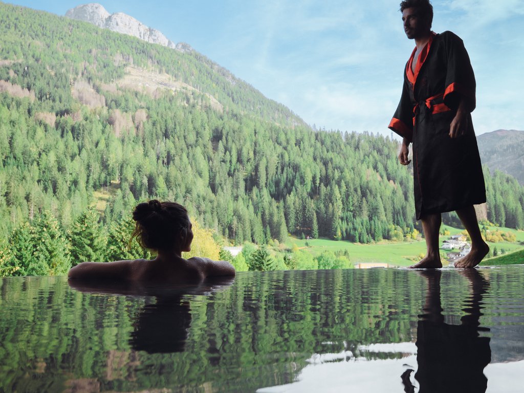 Hotel Latemar con vista sulle Dolomiti Donna in piscina con uomo in accappatoio vicino vista montagne verdi