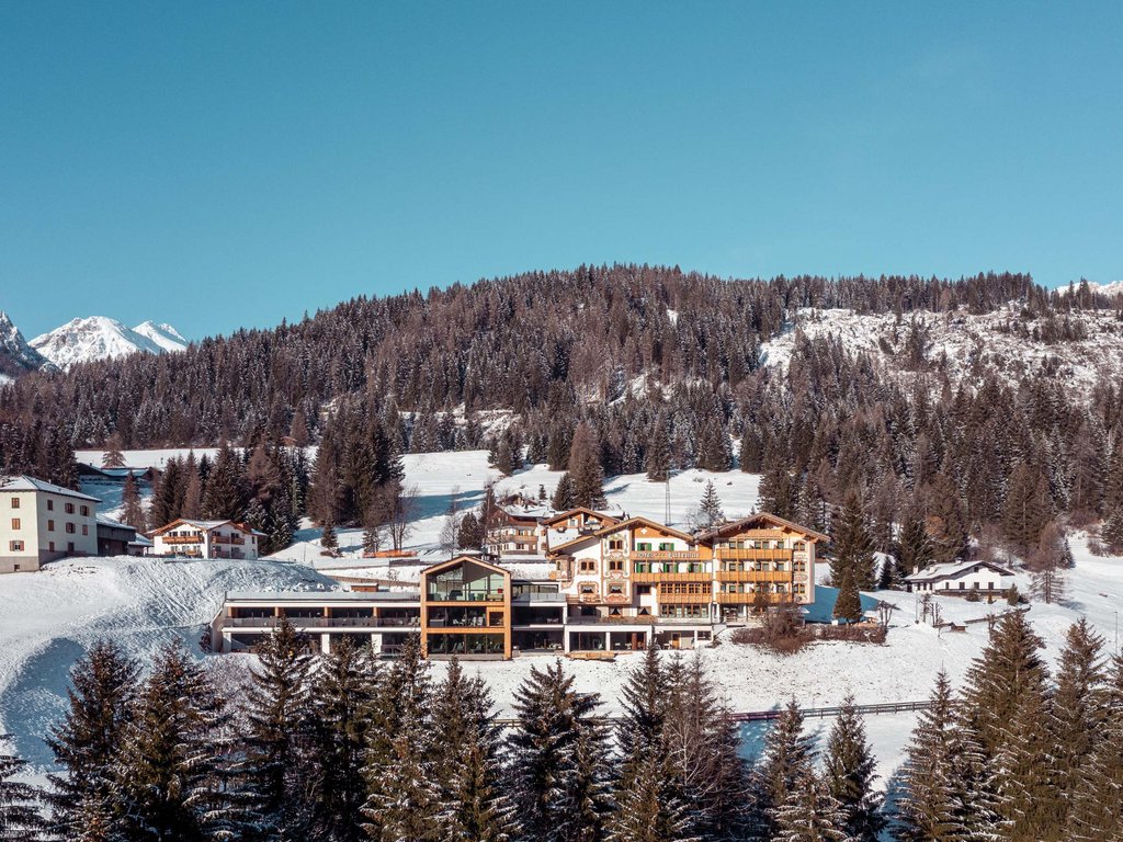 Soraga, l’Hotel Latemar e la cultura ladina Hotel in montagna con paesaggio invernale e alberi innevati