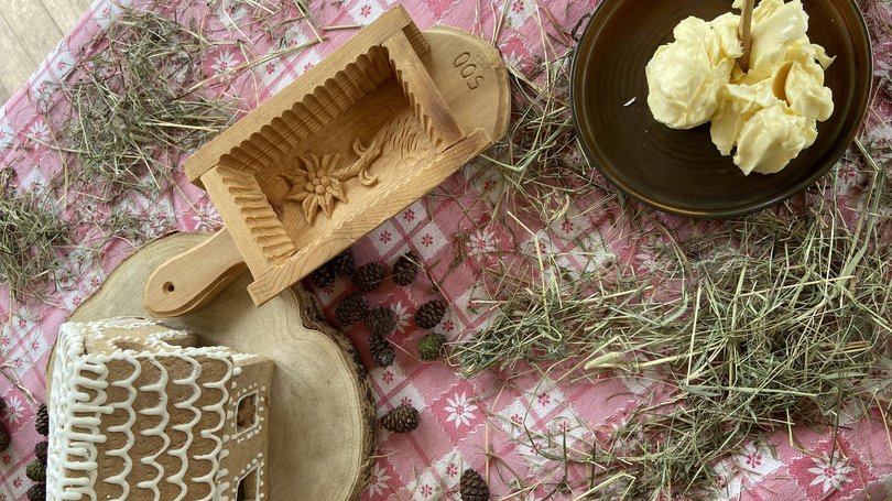 Val di Fassa: wandern, biken, erleben Lebkuchenhaus, Schüssel mit Butter, Holzform und Heu auf Tischdecke