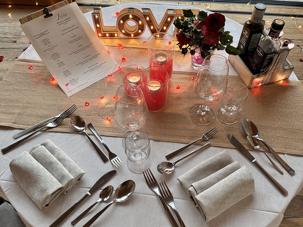 Sulla pista ciclabile, da Moena alla vostra oasi romantica Tavolo apparecchiato con candele, fiori e decorazione luminosa LOVE