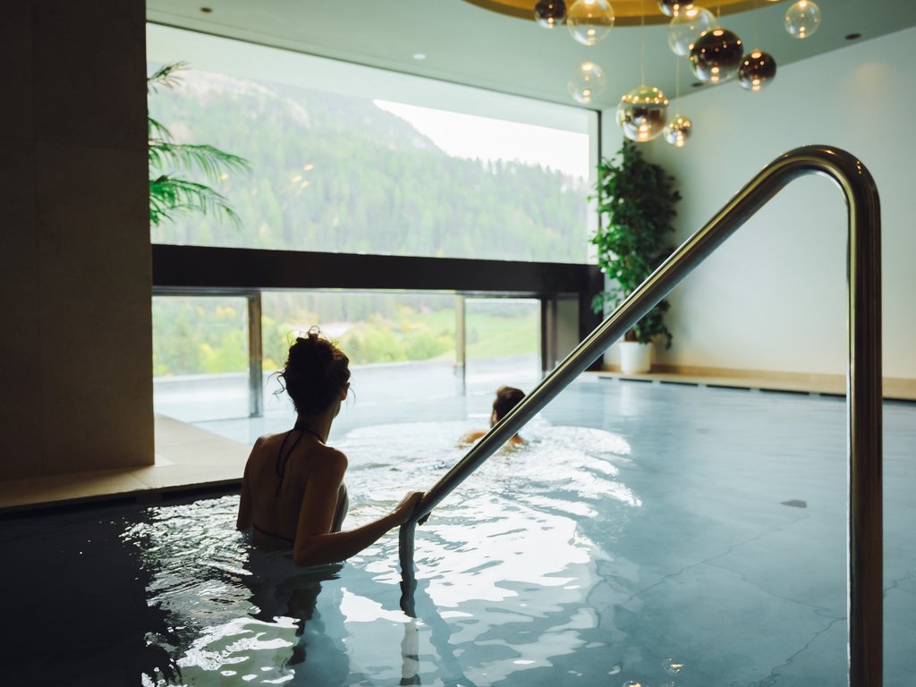 Barrierefreies Hotel im Val di Fassa: das Latemar Zwei Frauen entspannen im Innenpool mit Bergblick