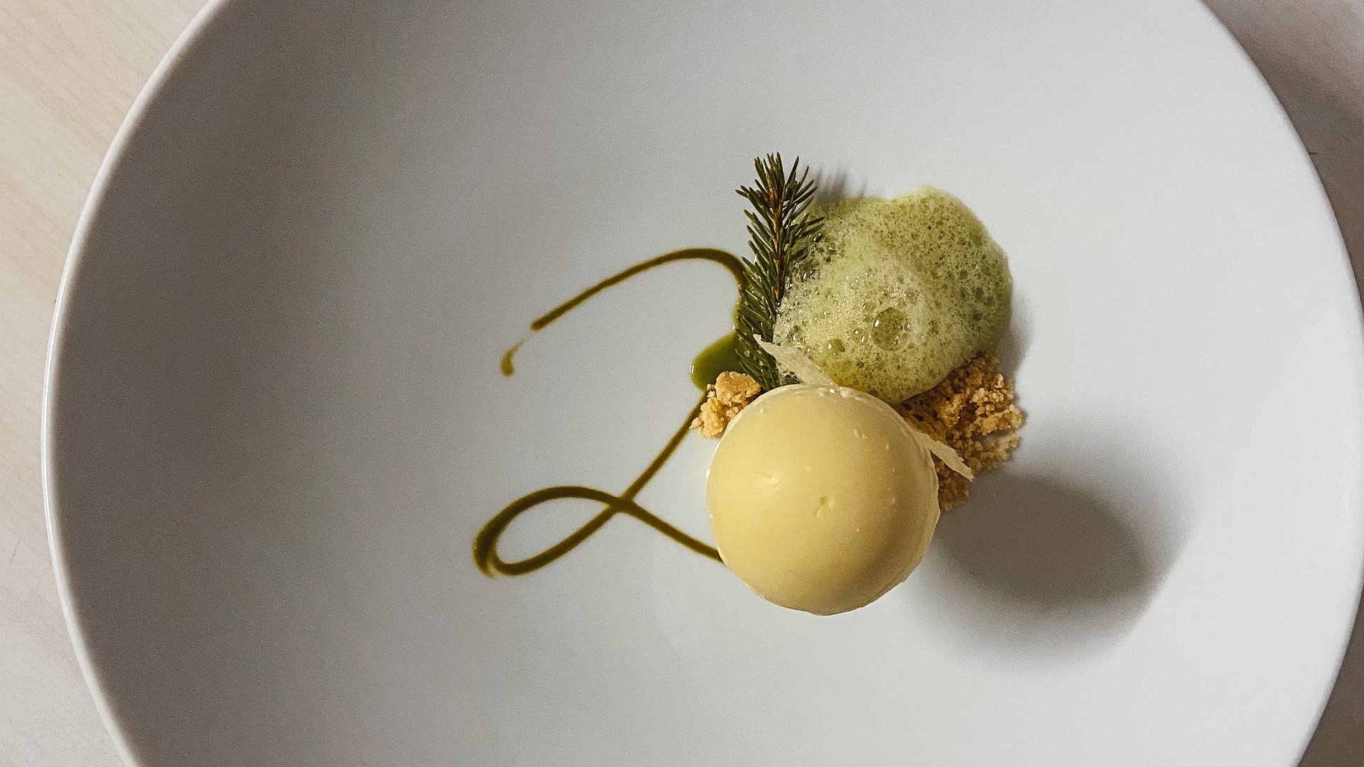 Soraga bei Südtirol im Trentino Gourmet-Dessert mit runder Mousse, grüner Dekoration und Schaum auf weißem Teller