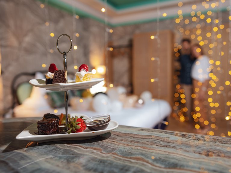 Hotel Latemar con vista sulle Dolomiti Dessert su piatto a due piani in un ambiente con luci soffuse e coppia sfocata