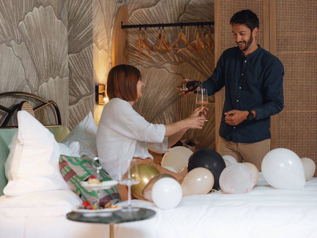 Moena: Unterkunft für Ihren Traumurlaub. Hotel Latemar! Paar stößt mit Weinglas in einem Zimmer mit Luftballons an