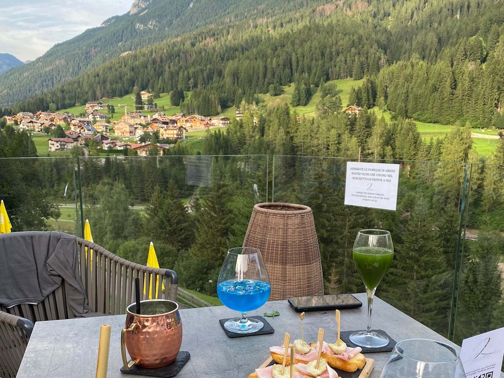 Noleggio bici a Soraga: un must in autunno all’Hotel Latemar Tavolo con aperitivi e antipasti con vista sulle montagne e villaggio