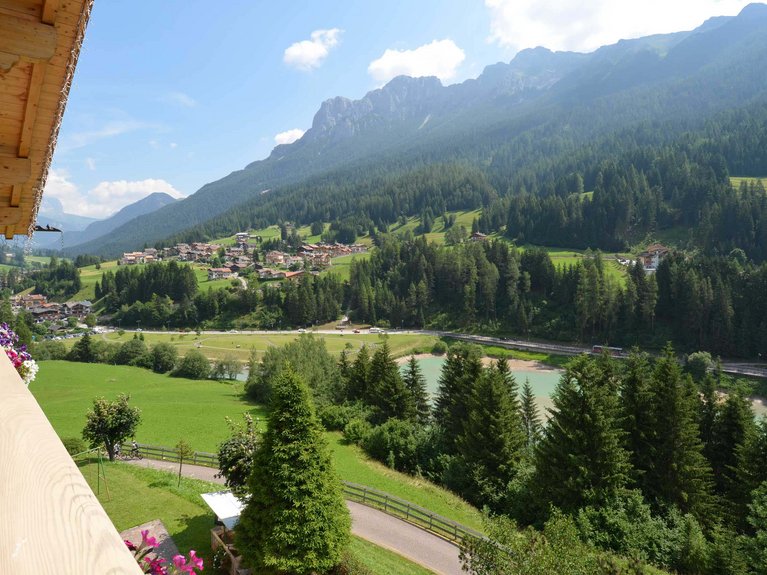 Hotel Latemar mit Dolomitenblick Panoramablick auf ein Bergdorf mit Bäumen, Fluss und klarem Himmel