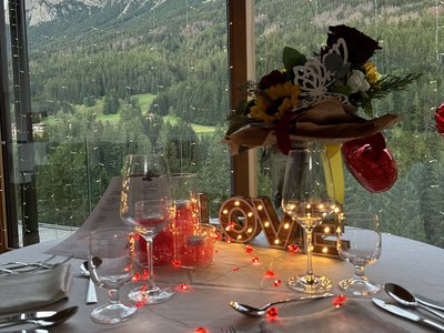 A Soraga il meteo è sempre ottimo per un Day Spa! Tavolo apparecchiato con decorazioni romantiche e vista sulle montagne dalla finestra