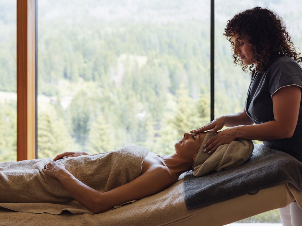 Soraga: dal lago alla piscina del Latemar Donna che riceve massaggio facciale in spa con vista sulla foresta