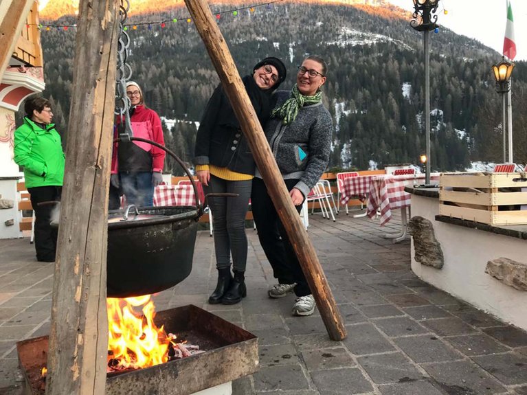 Dalla webcam il Latemar è bello, ma dal vivo è un sogno! Persone vicino a una grande pentola appesa sopra un fuoco all'aperto in montagna