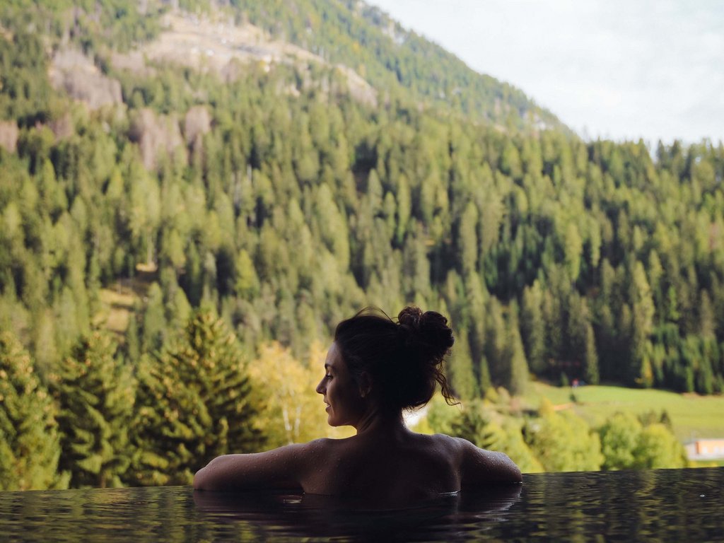 Soraga di Fassa: Urlaub in und mit der Natur Frau entspannt im Pool mit Blick auf grüne Berge