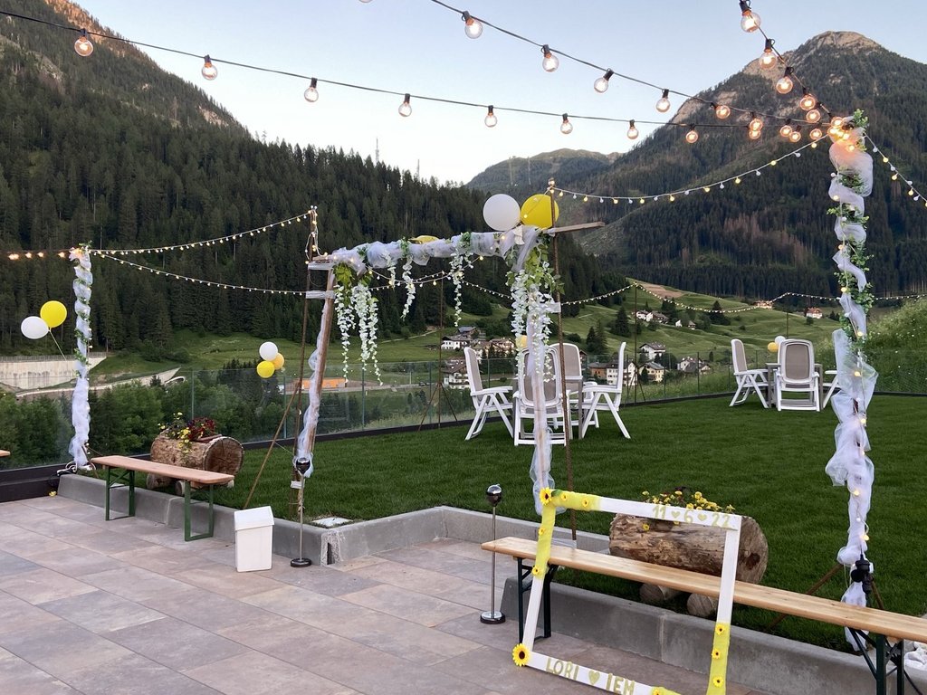 Val di Fassa: wandern, biken, erleben Terrasse für Veranstaltung mit Lichterketten, Luftballons und Bergen im Hintergrund
