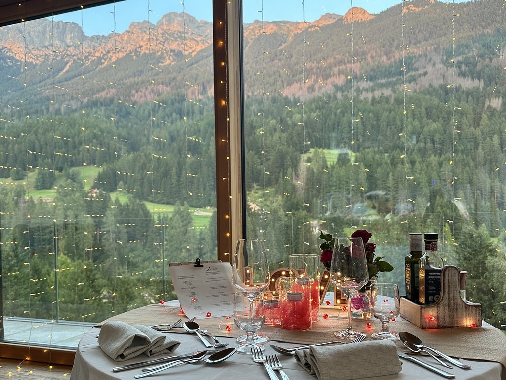 Fassatal: Radweg für romantische Momente Eingedeckter Tisch mit Bergblick durch großes Fenster