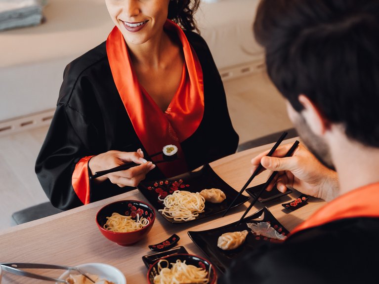 Urlaub im Fassatal: Erholung pur Paar isst Sushi und Nudeln in schwarzen Kimonos mit roten Details