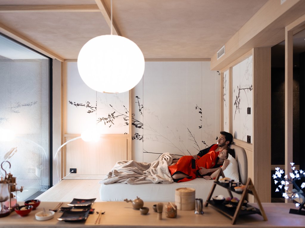 Val di Fassa: wandern, biken, erleben Paar entspannt sich in modernem Zimmer mit Essen und gedämpftem Licht