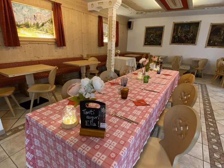 Dalla webcam il Latemar è bello, ma dal vivo è un sogno! Tavolo apparecchiato con tovaglia rossa a quadri e decorazioni in una stanza rustica