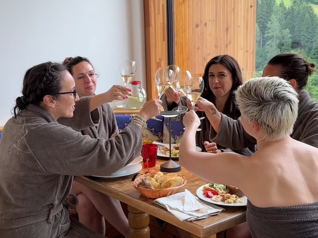 A Soraga il meteo è sempre ottimo per un Day Spa! Gruppo di donne in accappatoi che brindano con calici di vino in un ristorante