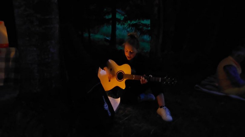 Val di Fassa: wandern, biken, erleben Mädchen spielt Gitarre abends beim Camping unter Lichterkette