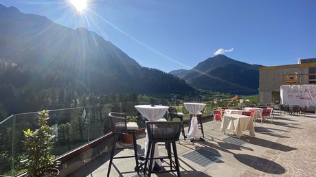 Picture gallery Terrace with tables and chairs overlooking sunny mountain landscape