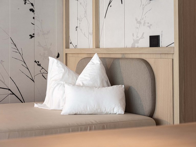 Urlaub im Fassatal: Erholung pur Modernes Bett mit weißen Kissen und beige gepolstertem Kopfteil